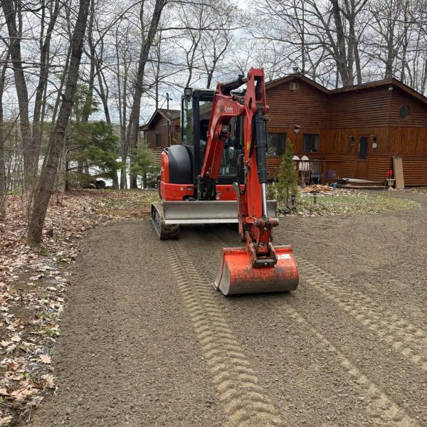 Orange excavator on a dirt path near wooden houses.