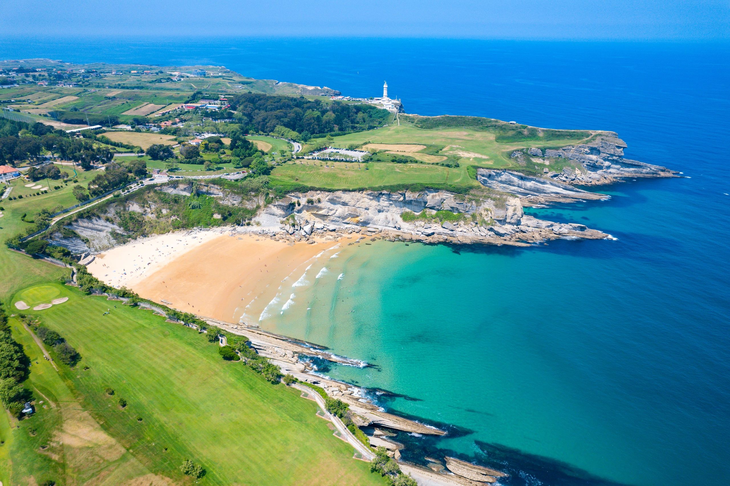 golf course on the coast of Spain with a beach in the centre of the image and cliffs around