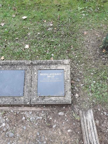 Memorial plaques on the ground surrounded by grass and dirt.
