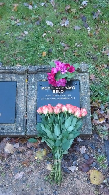 Grave with flowers honoring Modiu Adebayo Belo, a beloved father and husband.