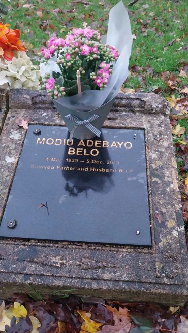 Grave of Modiu Adebayo Belo with flowers laid on top.