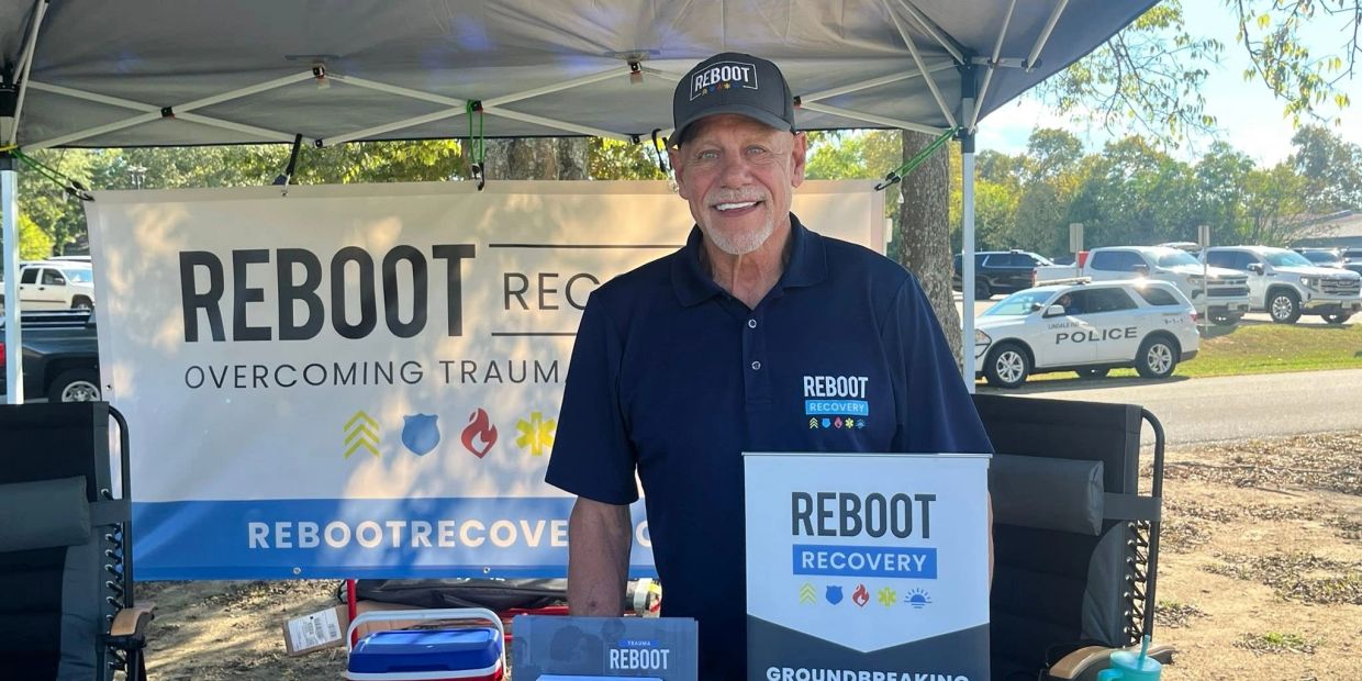 Man at a booth promoting Reboot Recovery for overcoming trauma.