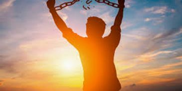 Silhouette of a person breaking free from chains at sunset.