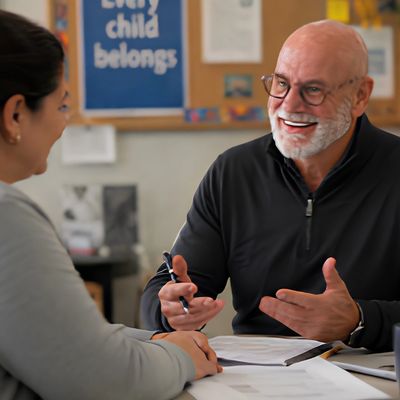 A smiling man and woman having a friendly discussion at a desk.