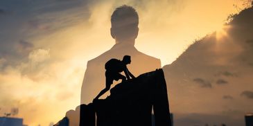 Silhouette of a climber overlaying a man's shadow against a sunset sky.