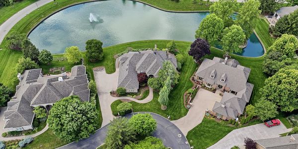 Aerial view of suburban houses near a pond with a fountain.