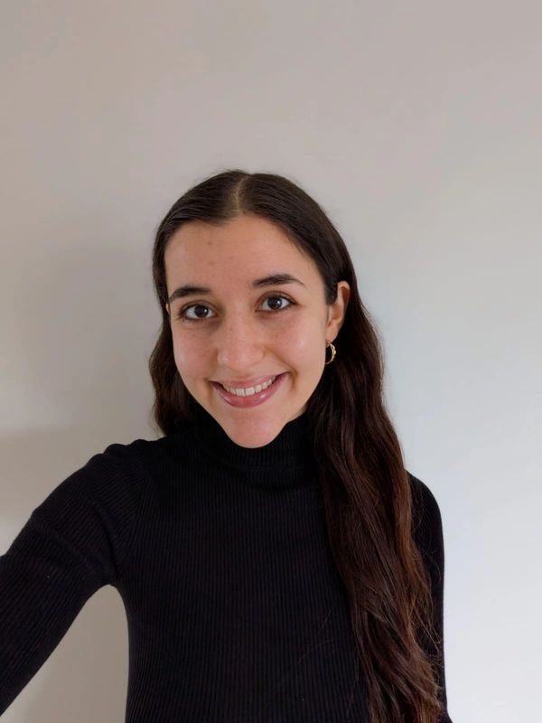 Young woman with long dark hair wearing a black turtleneck, smiling.