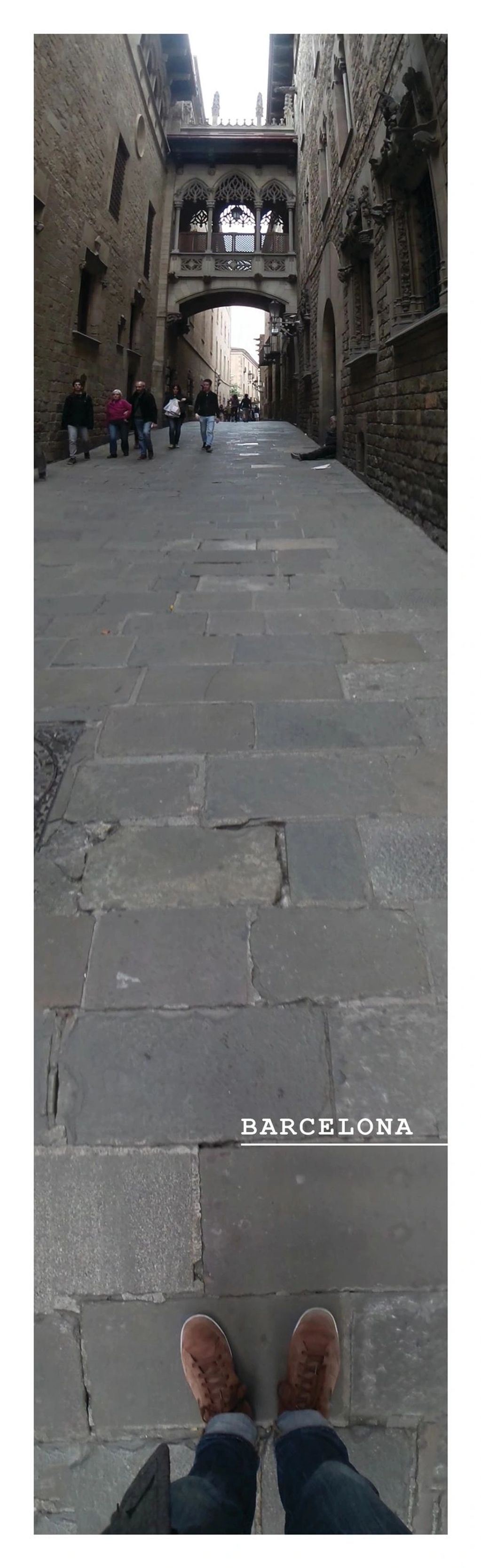 View of people walking in a historic stone street in Barcelona.
