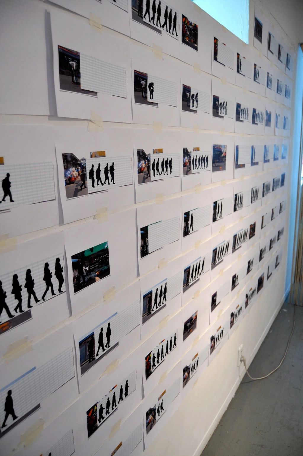 Wall with taped photos and shadow silhouettes in sequence.