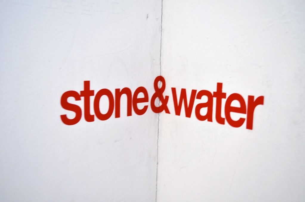 Red text 'stone&amp;water' on a white corner wall.