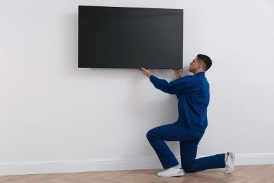 Technician mounting a flat screen TV on a wall.