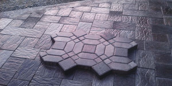 Stacked hexagonal paving stones resting on a patterned stone floor outdoors.