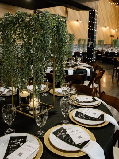 Elegant table setting with greenery centerpiece and gold-rimmed plates at a formal event.