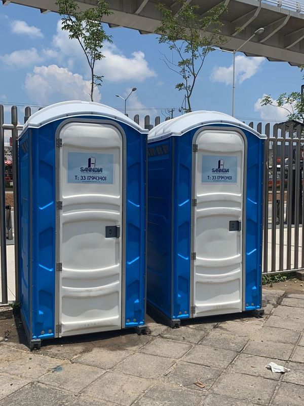 Two blue and white portable toilets standing outdoors near a fence.