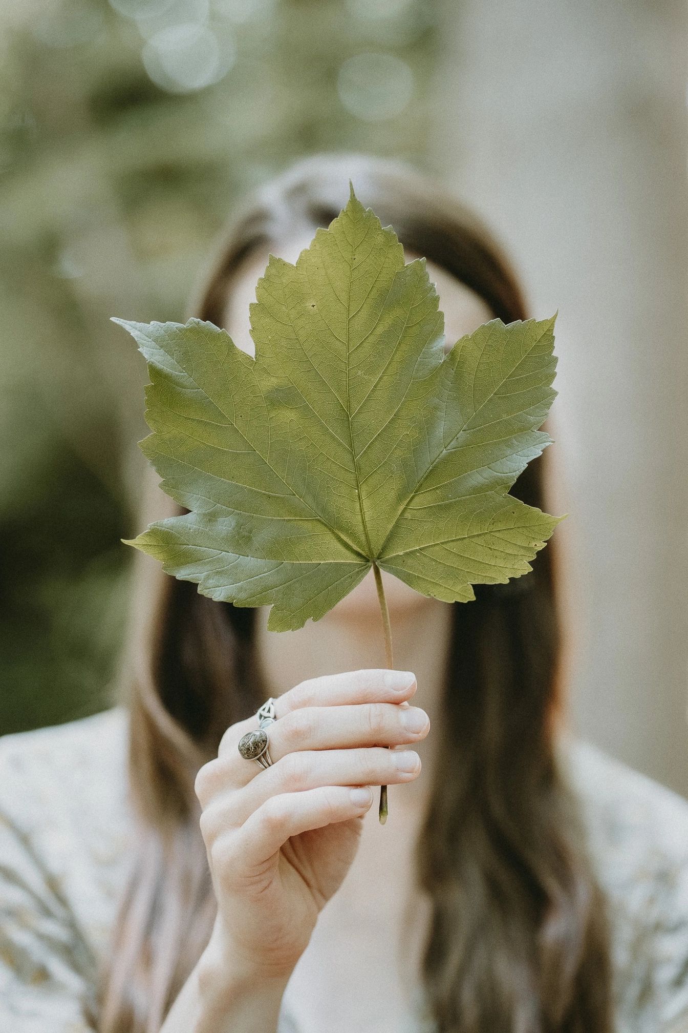 Woman holding leaf in front of her face