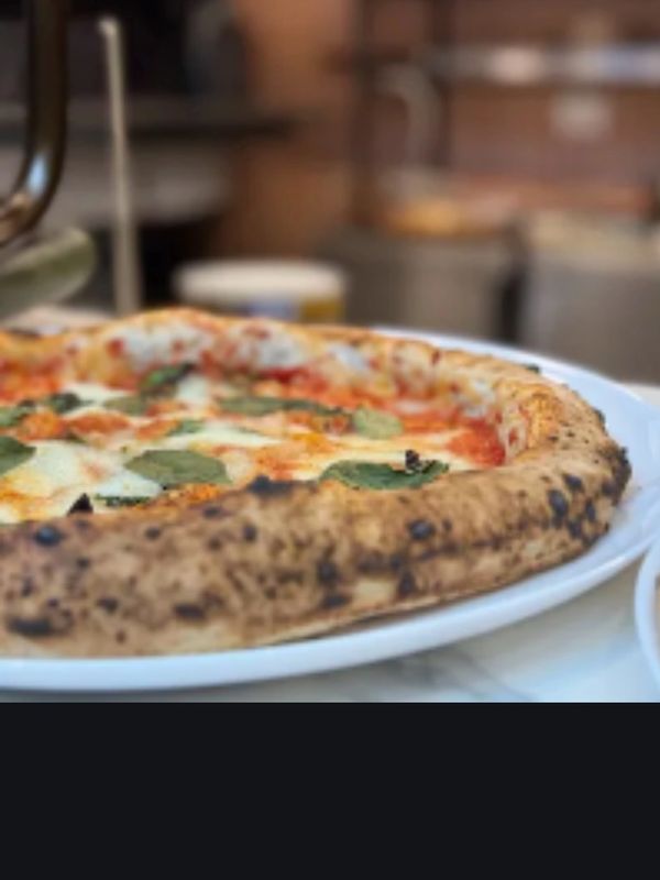 Close-up of a freshly baked pizza with basil leaves on a white plate.