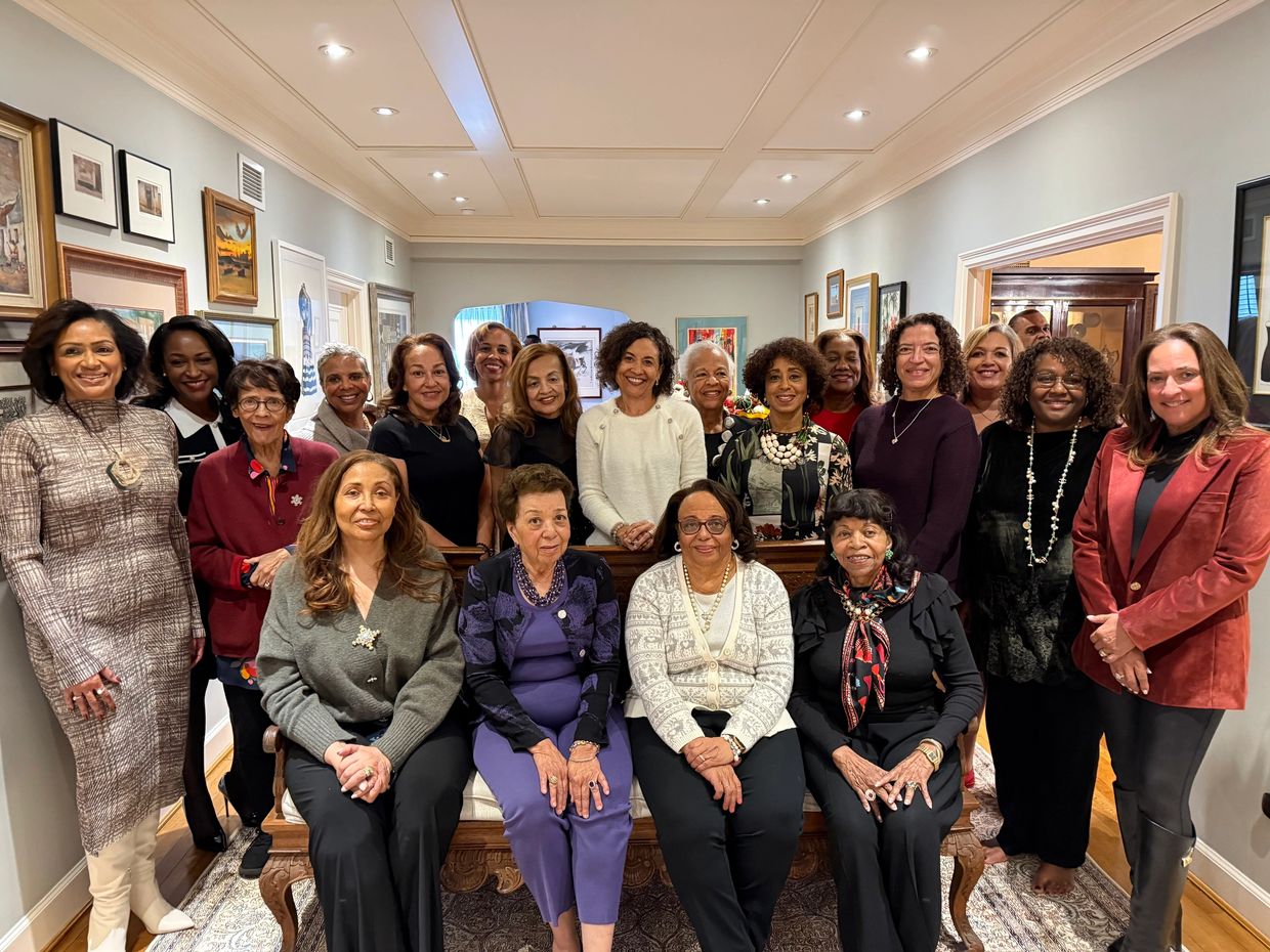 A group of women posing together indoors, smiling at the camera.