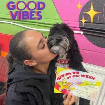 Woman lovingly kisses her dog holding a "Star of the Week" certificate.