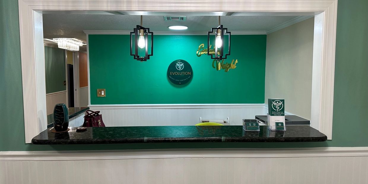Reception desk with green wall and modern lights at Evolution Weight Loss Center.