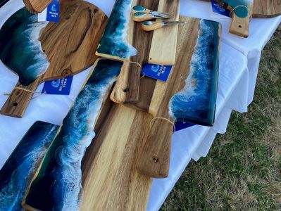 Wooden cutting boards with ocean wave resin art displayed on a table.
