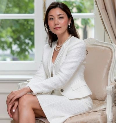 Elegant woman in white suit sitting gracefully on a luxurious chair.