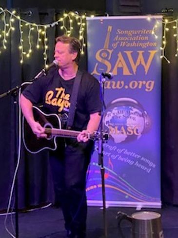 Man playing guitar and singing on stage at a music event.