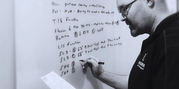 Dr. Eric Lambert documenting patient evaluation findings on a whiteboard