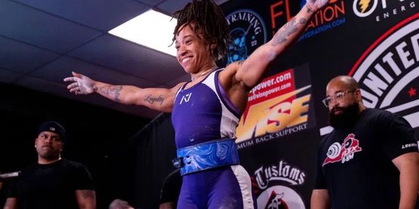 Smiling weightlifter with arms outstretched during competition.