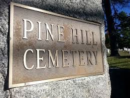 Stone sign reading Pine Hill Cemetery on a granite base.