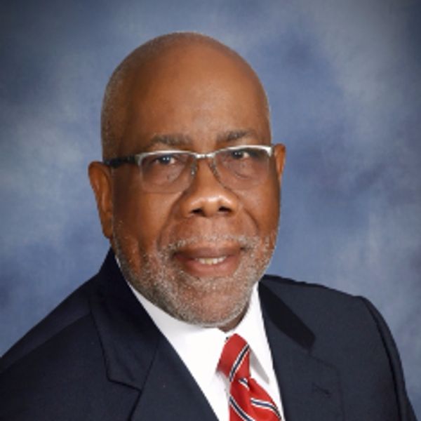 Professional portrait of a man in a suit and tie with glasses.