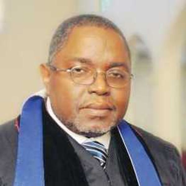 Portrait of a man wearing glasses and formal academic attire.