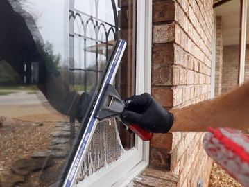 An exterior window getting cleaned with a squeegee, removing all dirt and film. 