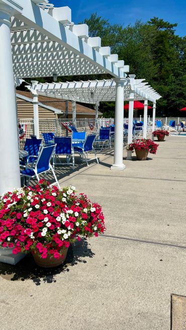 Outdoor poolside seating with pergola and flowers