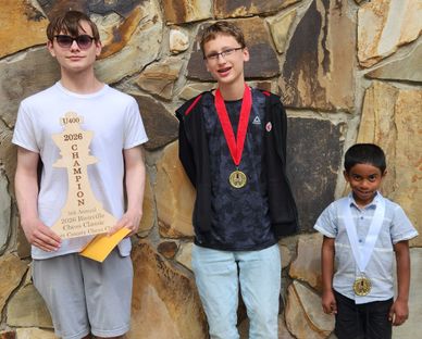 Three boys proudly display their awards against a stone wall.