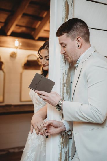 Bride and groom holding hands around a corner, reading vows before the ceremony.
