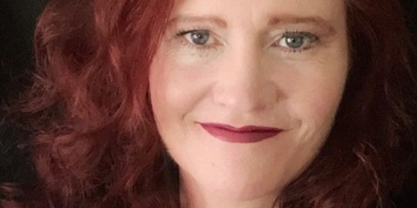 Close-up of a woman with red hair and dark lipstick.