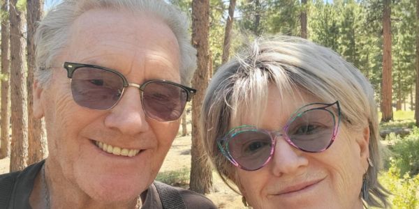 Smiling elderly couple wearing sunglasses outdoors.