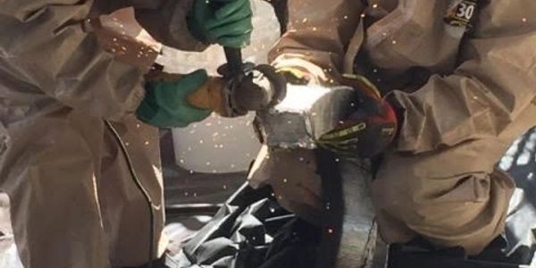 Two workers grinding metal, sparks flying.