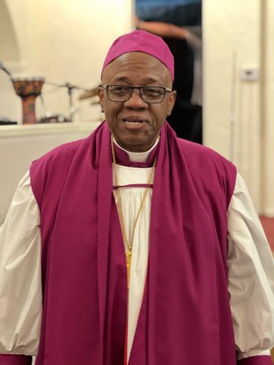 Man in religious attire with glasses and pink vestments.