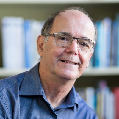 Smiling man with glasses and blue shirt in a library.