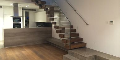 Modern interior with floating wooden stairs and open kitchen area.