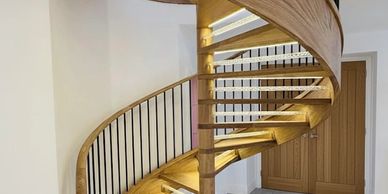 Elegant wooden spiral staircase with black metal railings in a modern home.