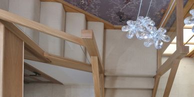 Top-down view of a wooden staircase with beige carpeting and a modern chandelier.