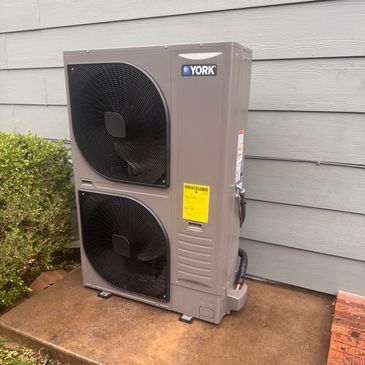 Outdoor York air conditioning unit against house wall.