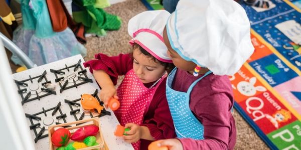 Two toddlers cooking on toy utensils