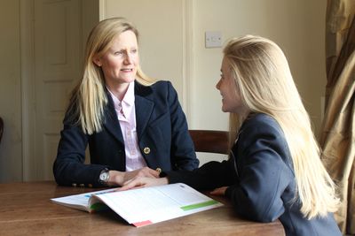 Two women in a discussion with a book on the table.