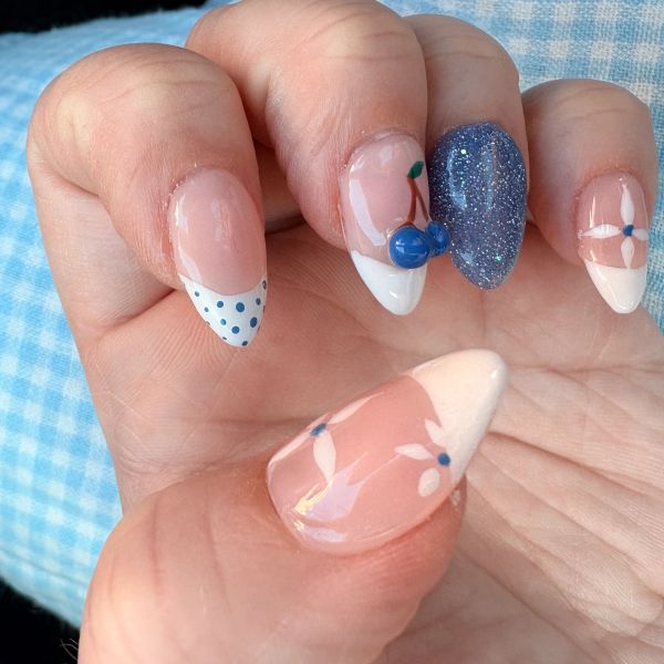 Elegant nails with floral and polka dot designs, accented with blue glitter and 3D details.