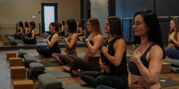 Group of women meditating in yoga studio.
