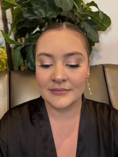 Woman with closed eyes and elegant makeup, wearing a black robe.