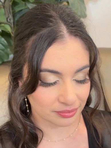 Woman with elegant makeup and soft curls looking down.